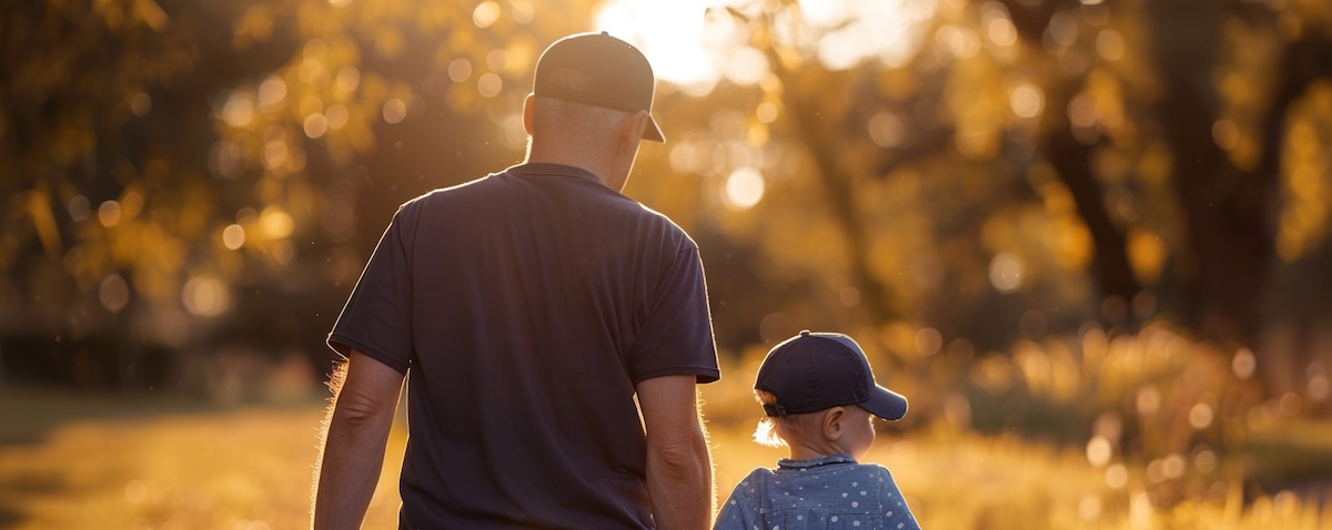 Vater und Kind von hinten mit gleicher Cap beim Spaziergang im Park